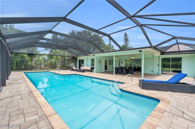 view of pool featuring glass enclosure, a patio area, and ceiling fan