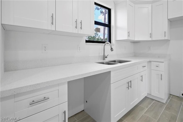 kitchen featuring light stone countertops, sink, and white cabinets