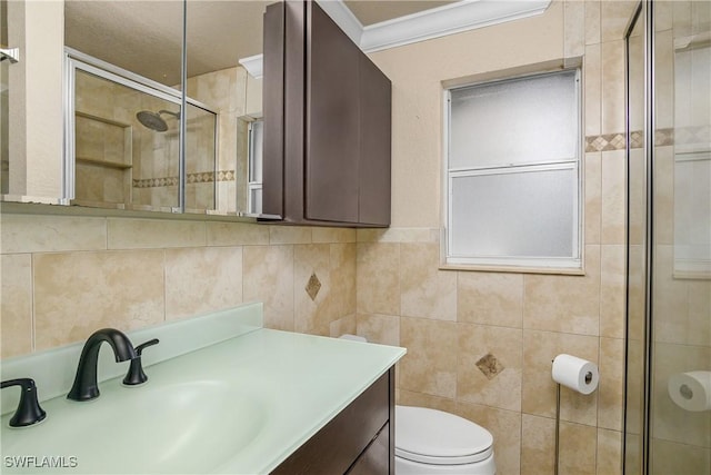 full bathroom featuring toilet, vanity, tile walls, ornamental molding, and a tile shower