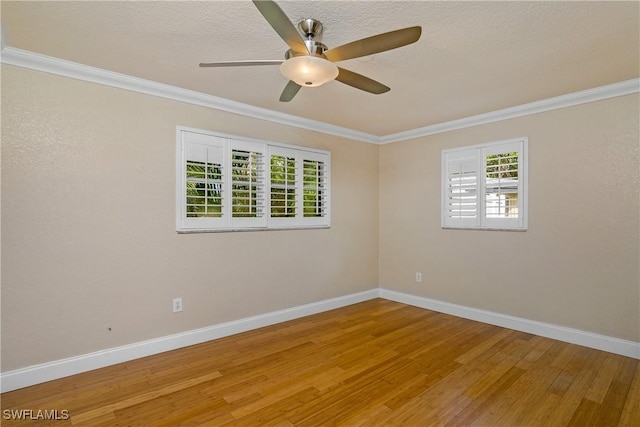 empty room with a healthy amount of sunlight, baseboards, ornamental molding, and wood finished floors