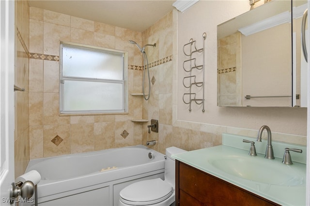 full bathroom featuring tiled shower / bath, vanity, toilet, and tile walls