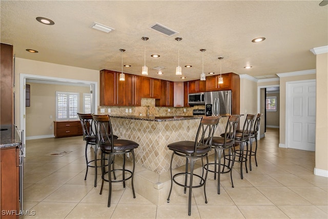 kitchen featuring hanging light fixtures, stainless steel appliances, a kitchen breakfast bar, ornamental molding, and decorative backsplash