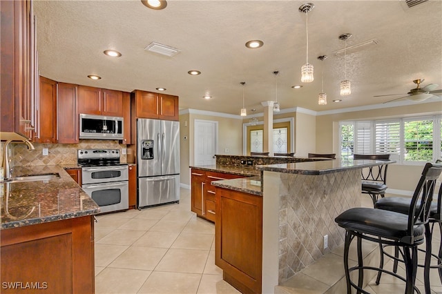 kitchen featuring appliances with stainless steel finishes, sink, pendant lighting, and dark stone counters