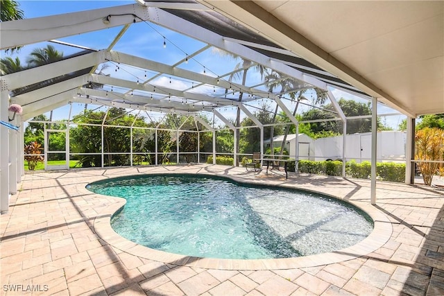 view of swimming pool with a lanai, a patio area, a shed, and a fenced in pool