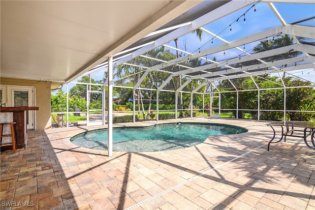 view of swimming pool featuring a lanai, an outdoor bar, and a patio area