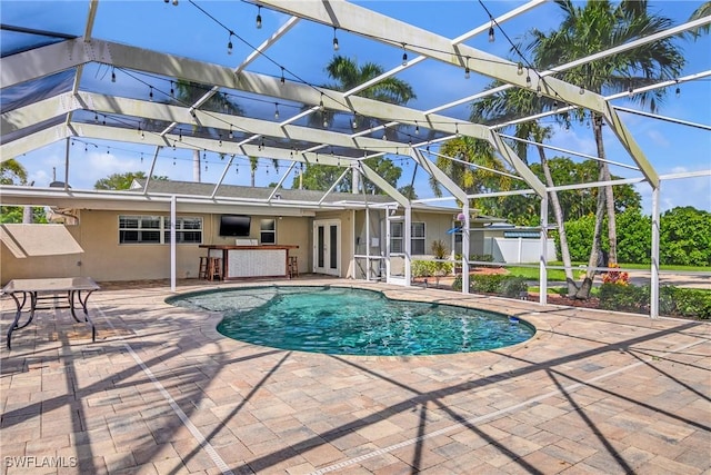 pool featuring outdoor dry bar, a patio, a lanai, and fence