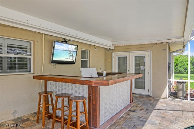 bar with stone finish flooring and french doors