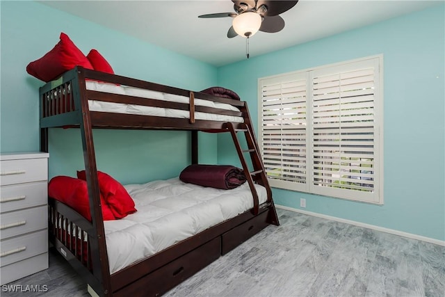 bedroom featuring multiple windows, ceiling fan, baseboards, and wood finished floors