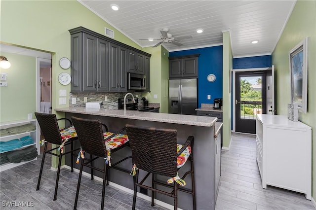 kitchen featuring a breakfast bar area, stainless steel appliances, a peninsula, visible vents, and tasteful backsplash