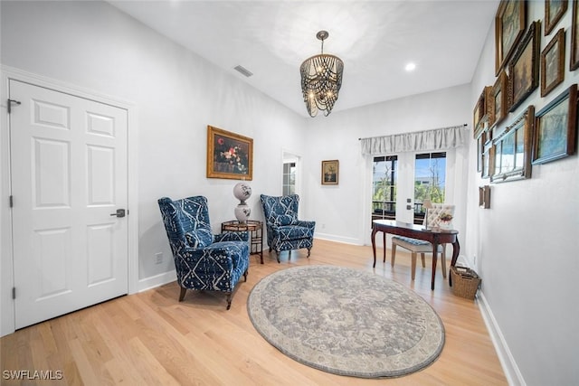 sitting room featuring french doors, a chandelier, and hardwood / wood-style floors