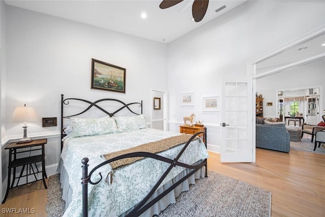 bedroom with ceiling fan, light hardwood / wood-style flooring, high vaulted ceiling, and french doors