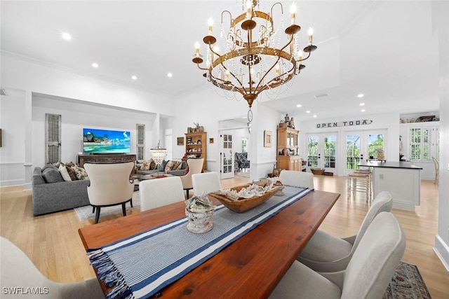 dining space with light wood-type flooring, french doors, a notable chandelier, and crown molding