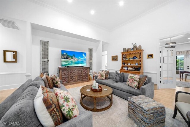 living room featuring light hardwood / wood-style floors, crown molding, and french doors