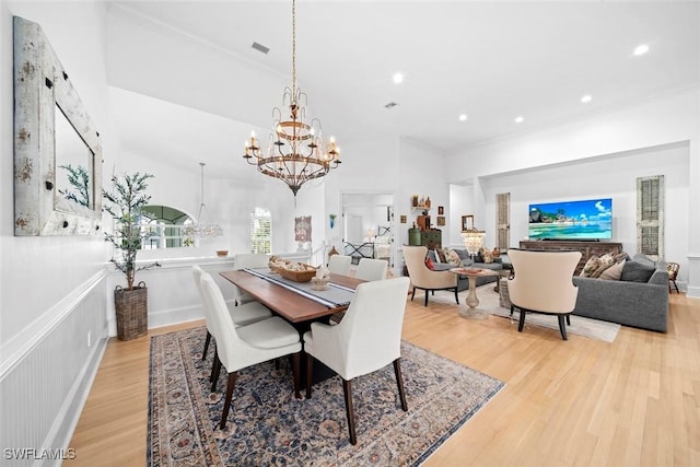 dining space with crown molding, a chandelier, and light wood-type flooring