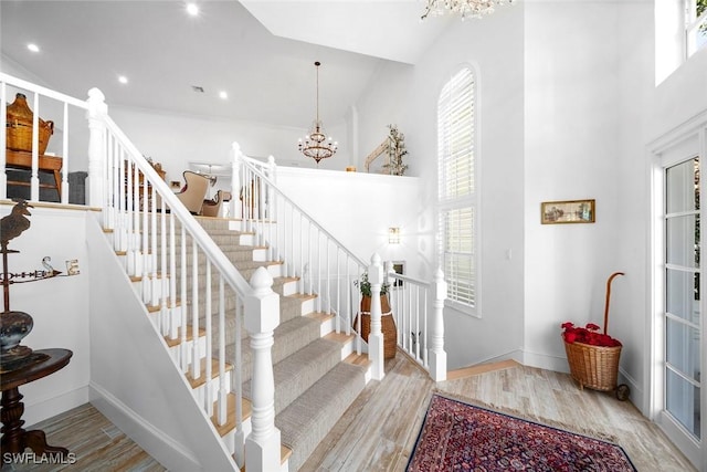 stairway featuring a healthy amount of sunlight, a chandelier, and hardwood / wood-style flooring