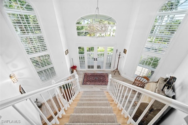 foyer with a towering ceiling, french doors, and a notable chandelier