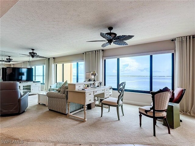 carpeted living room with ceiling fan, a textured ceiling, and a water view