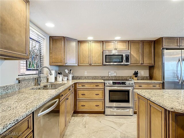 kitchen with light stone countertops, sink, a textured ceiling, light tile patterned flooring, and stainless steel appliances