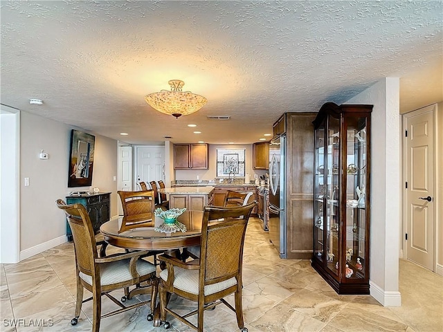 dining room with a textured ceiling, marble finish floor, visible vents, and baseboards