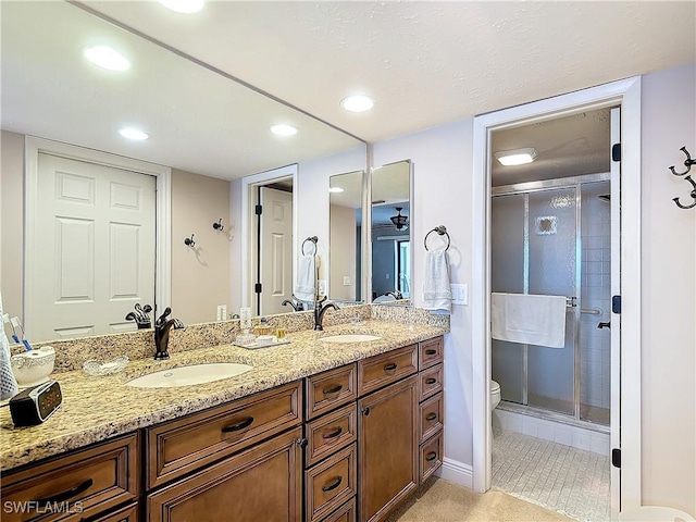 full bath with double vanity, a stall shower, a sink, and toilet