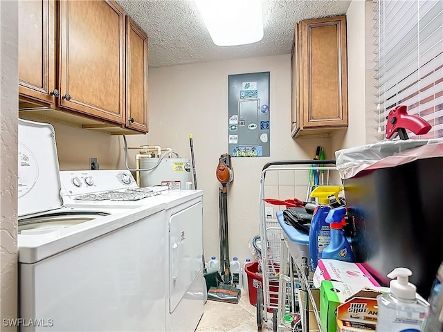 laundry room featuring washer and dryer, electric water heater, cabinet space, and a textured ceiling