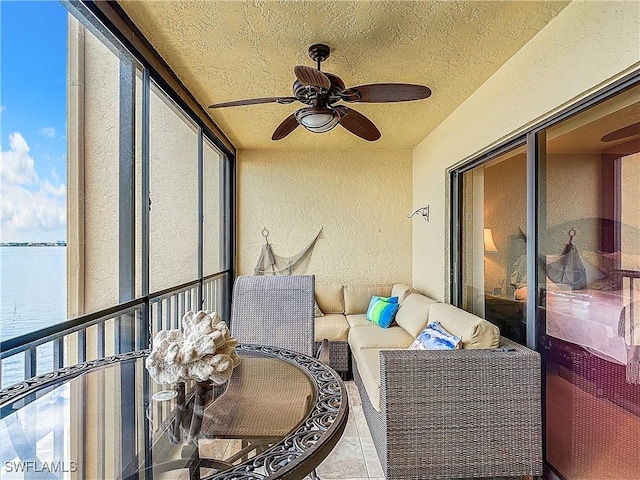 sunroom featuring a ceiling fan, a water view, and plenty of natural light