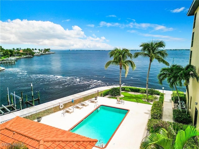 community pool with a patio area, a dock, a water view, and boat lift