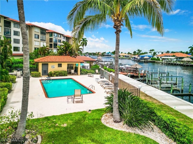 community pool with a patio area, a water view, and fence