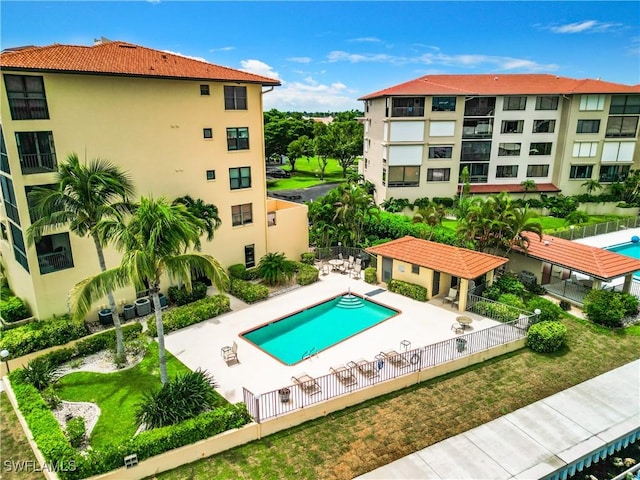 community pool featuring fence, a lawn, and a patio