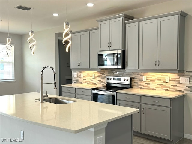 kitchen featuring appliances with stainless steel finishes, hanging light fixtures, sink, and tasteful backsplash