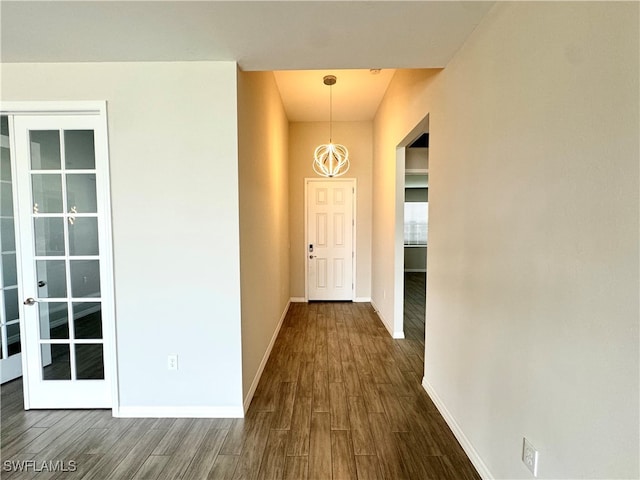 hall with an inviting chandelier, dark hardwood / wood-style floors, and french doors