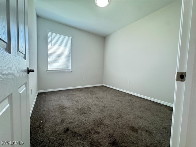 spare room with dark colored carpet