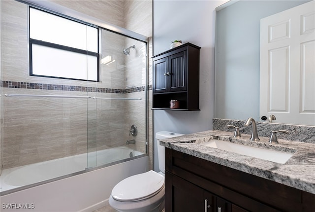 full bathroom featuring combined bath / shower with glass door, vanity, and toilet