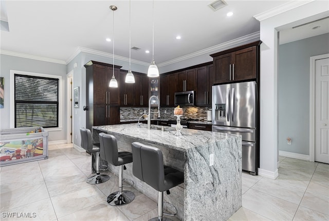 kitchen with appliances with stainless steel finishes, dark brown cabinets, decorative backsplash, light stone countertops, and hanging light fixtures