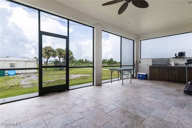 unfurnished sunroom featuring ceiling fan and plenty of natural light