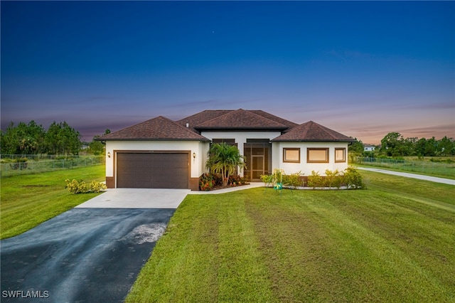 prairie-style home with a garage and a yard