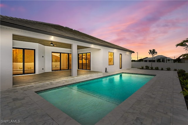 pool at dusk with a patio area