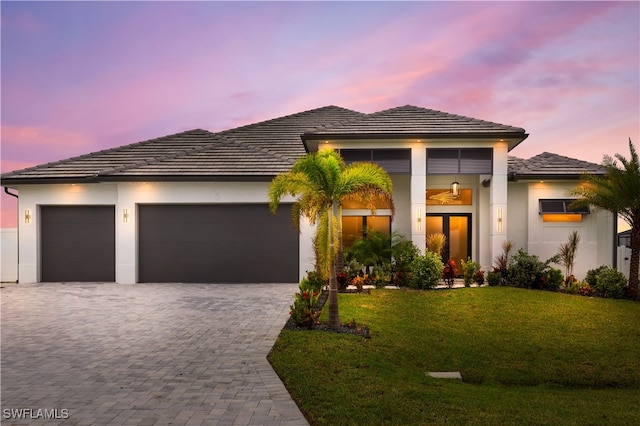 prairie-style home with french doors, a yard, and a garage