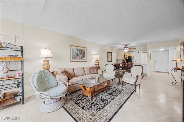 living room with a textured ceiling, ceiling fan, and light tile patterned flooring