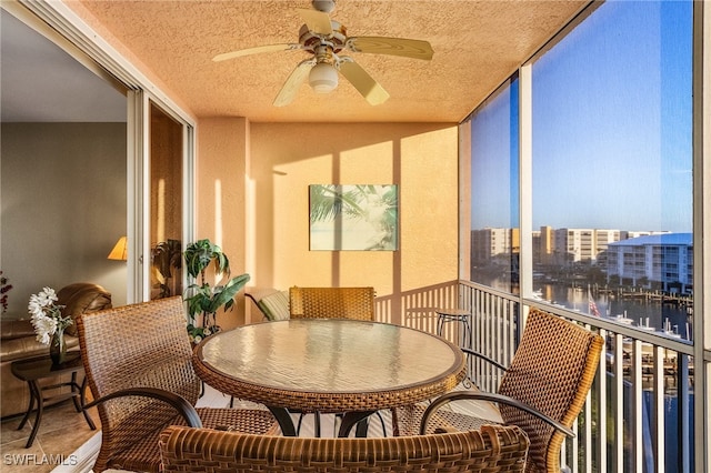 sunroom featuring a water view and ceiling fan