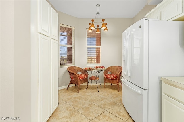 kitchen with white cabinets, hanging light fixtures, light tile patterned floors, a chandelier, and white fridge