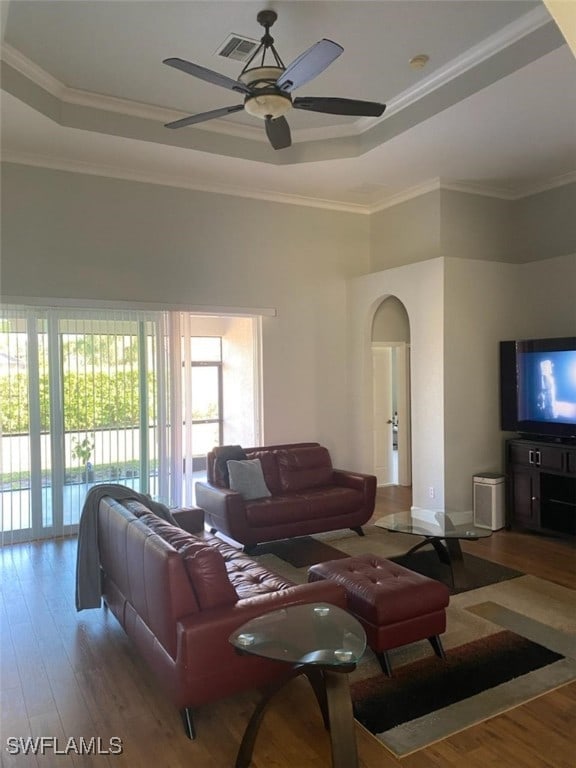 living room featuring ornamental molding, a raised ceiling, hardwood / wood-style floors, and ceiling fan