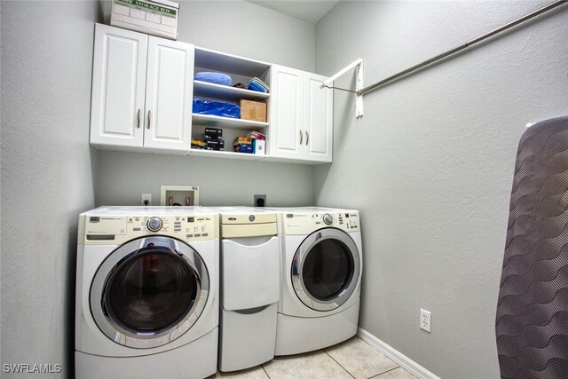 laundry room with washer and dryer, cabinets, and light tile patterned flooring