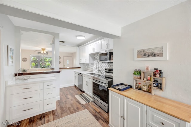 kitchen with light wood-type flooring, stainless steel appliances, white cabinetry, sink, and tasteful backsplash