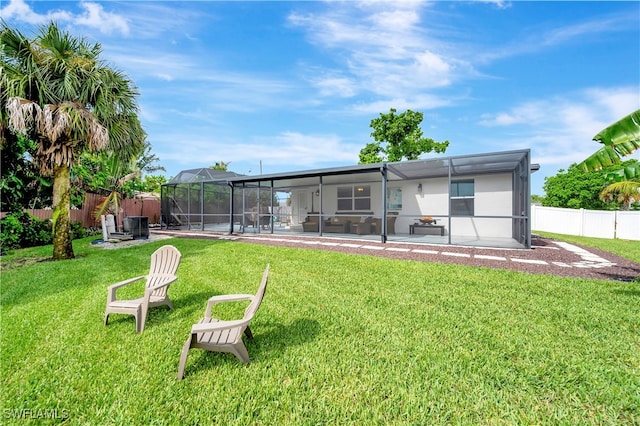 rear view of property featuring glass enclosure, a patio area, and a lawn