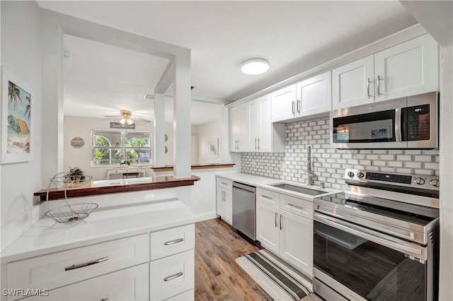 kitchen featuring white cabinets, appliances with stainless steel finishes, light hardwood / wood-style floors, sink, and decorative backsplash