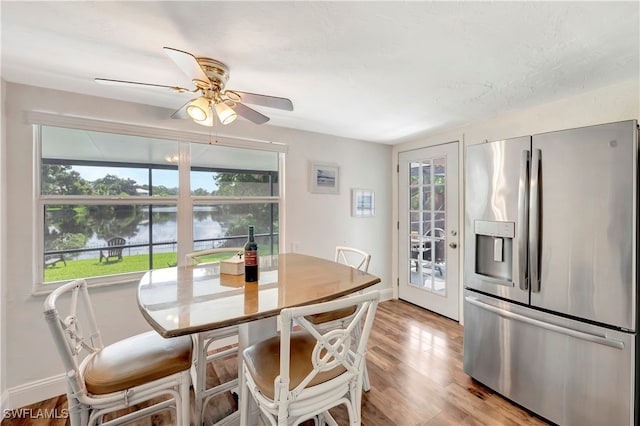 dining area featuring a water view, ceiling fan, and light hardwood / wood-style flooring