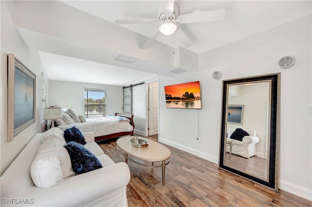 living room featuring a barn door, ceiling fan, and hardwood / wood-style flooring