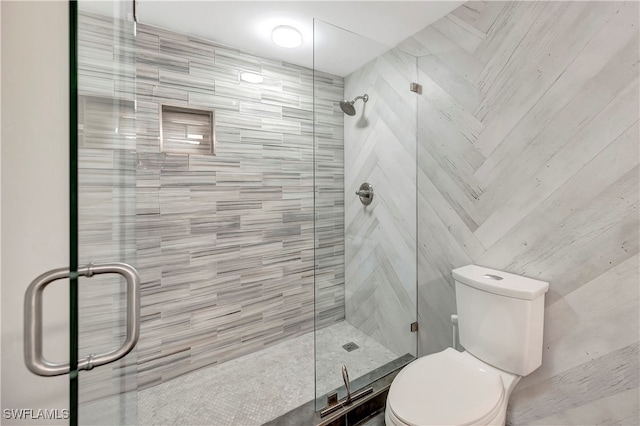 bathroom featuring toilet and a shower with door