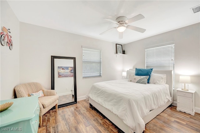 bedroom with ceiling fan, multiple windows, and light hardwood / wood-style floors